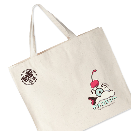 An off-white canvas tote bag with two shoulder straps, featuring a circular black logo on the upper left and a Amiko Legends character.