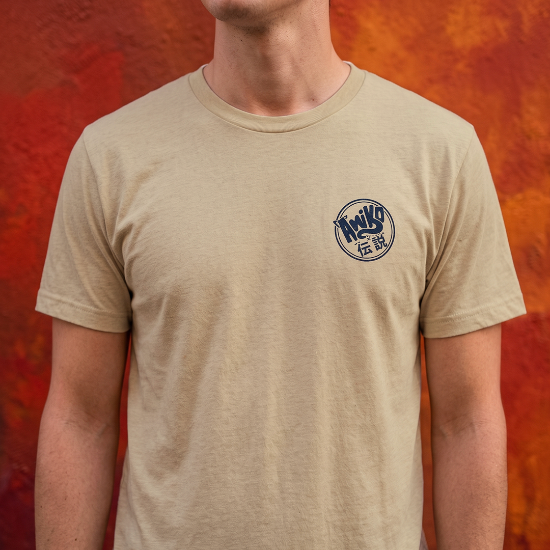 A man wearing a beige crewneck t-shirt with a Amiko Legends logo on navy blue  on the left chest, set against a textured orange and red background.