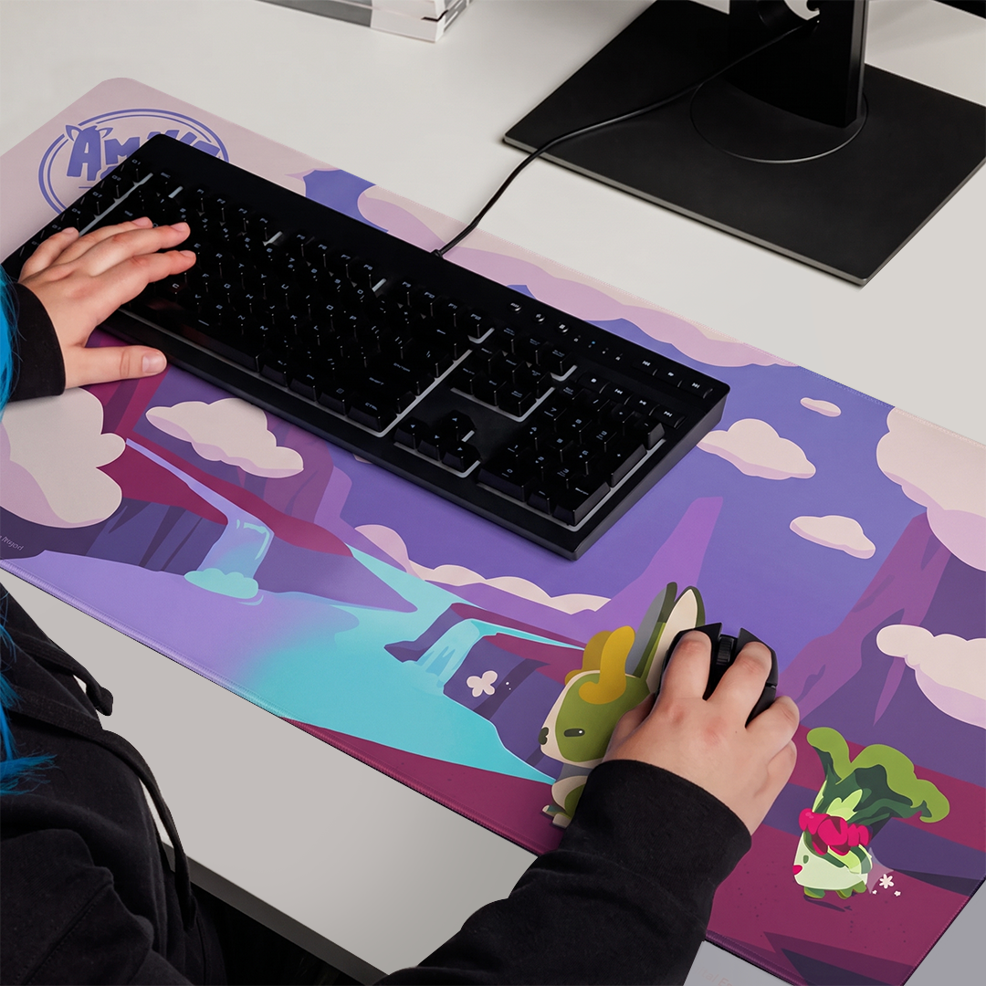 A Amiko Legends Gaming Mouse Pad, featuring characters, under a keyboard and mouse, with a person's hands using them.