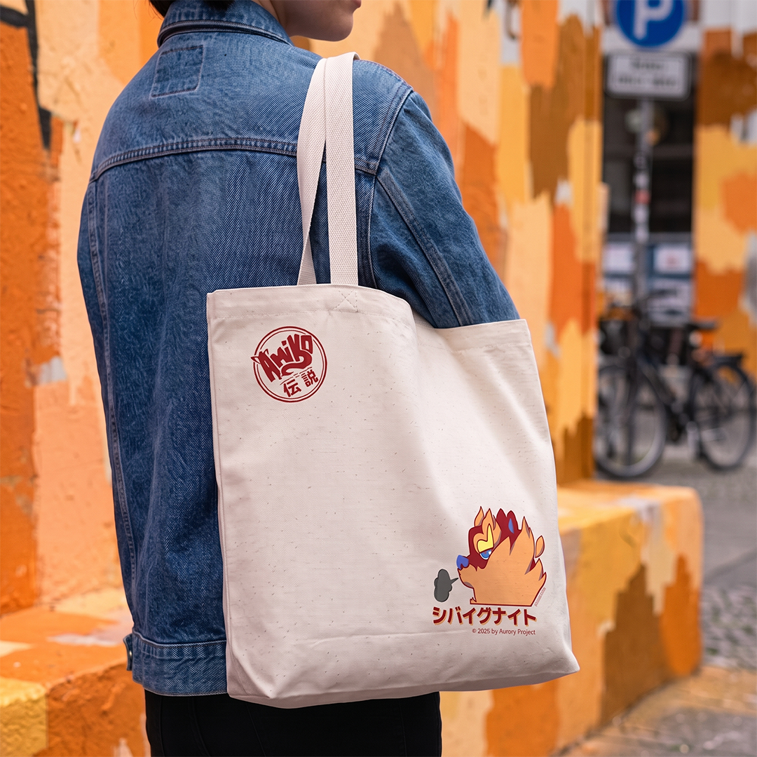 A person carries a cream canvas tote bag eatures a red circular logo on the upper left and a Amiko Legends Character graphic with Japanese text on the lower right.